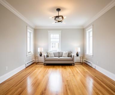 Refreshed living room with fresh paint, new trim, updated lighting, and refinished hardwood floors