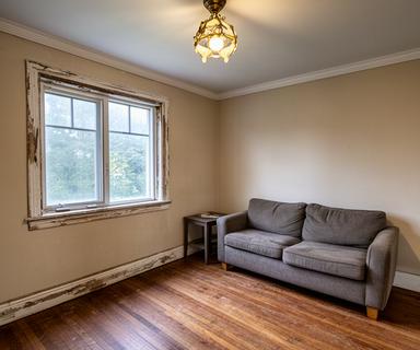 Tired living room in a Quebec home before a whole-home refresh with worn trim and dated lighting