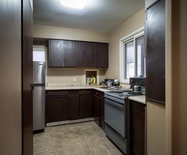 Closed-off older kitchen in a Baie-Comeau home before renovation with dark cabinets and limited counter space